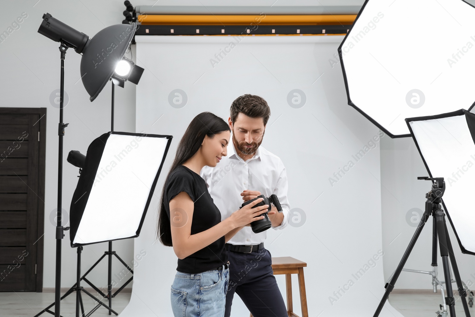 Photo of Professional photographer and model looking at pictures on camera in modern studio