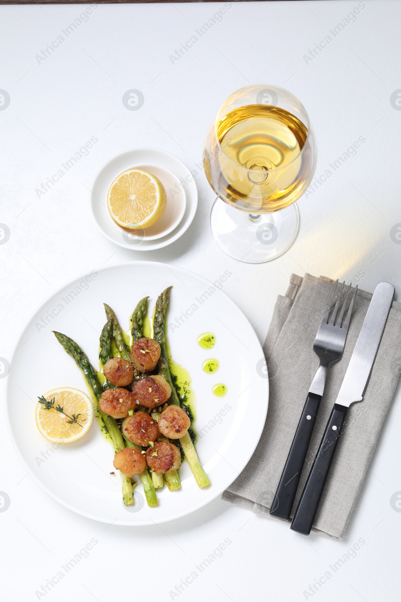 Photo of Delicious fried scallops with asparagus, lemon and thyme served on white table, flat lay