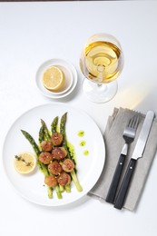 Delicious fried scallops with asparagus, lemon and thyme served on white table, flat lay