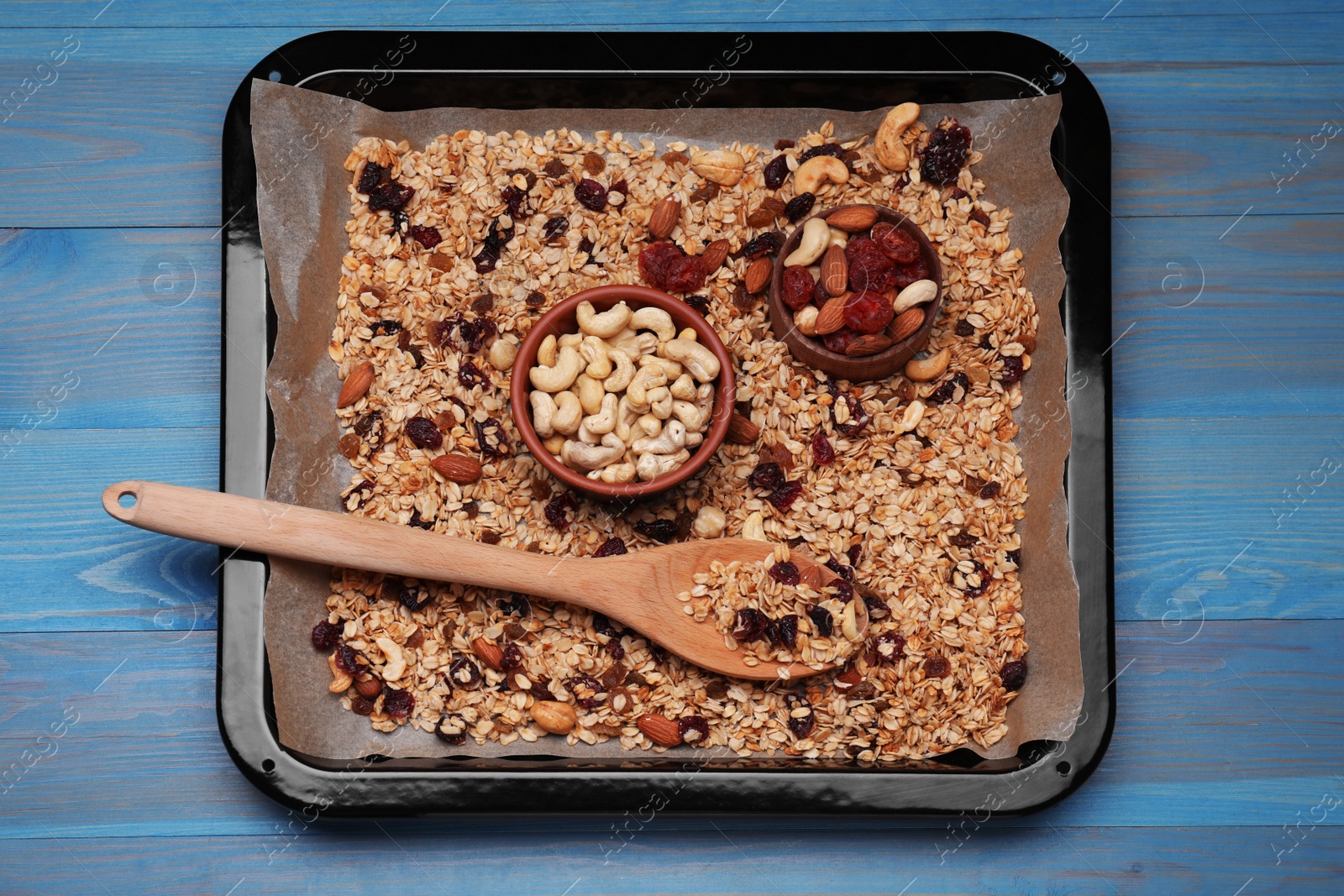 Photo of Tray with tasty granola, nuts and dry fruits on blue wooden table, top view