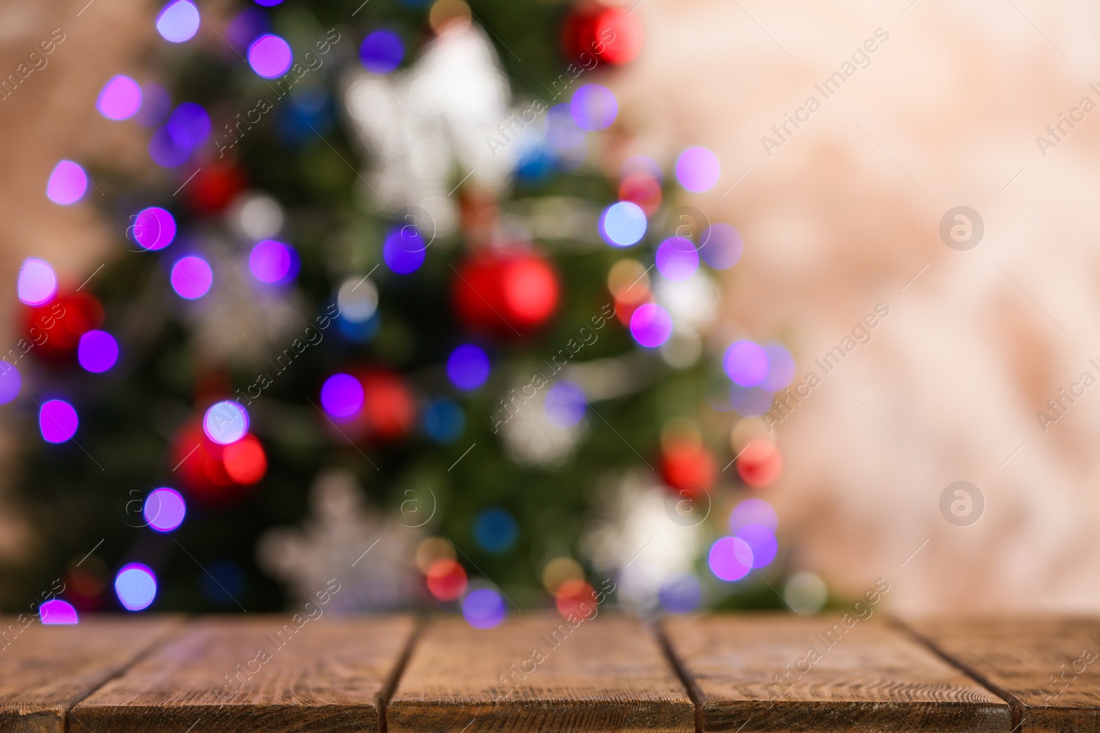 Photo of Empty wooden table and blurred fir tree with Christmas lights on background, bokeh effect. Space for design