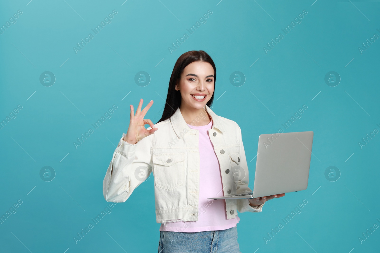 Photo of Young woman with modern laptop on light blue background