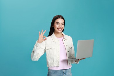 Young woman with modern laptop on light blue background