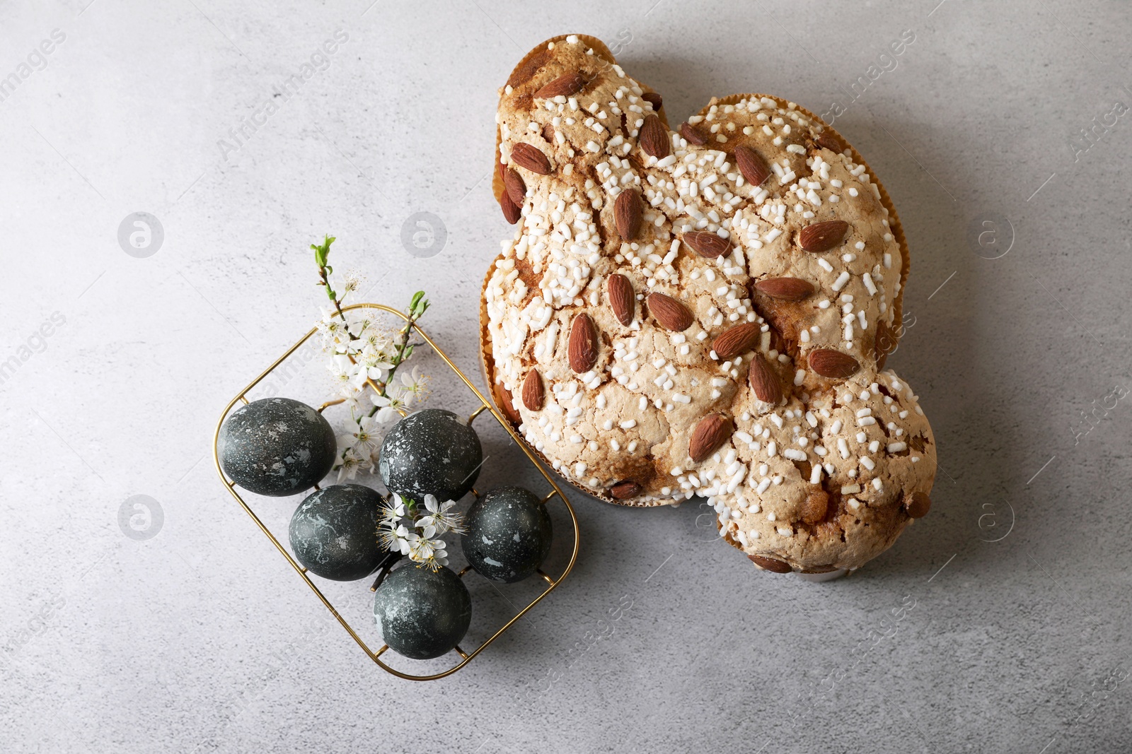 Photo of Delicious Italian Easter dove cake (Colomba di Pasqua) and decorated eggs on grey table, flat lay