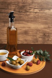 Photo of Oil, olives and tree twig on brown table