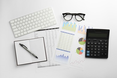 Photo of Accounting documents, stationery, glasses and computer keyboard on white table, flat lay