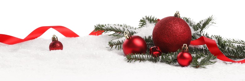 Photo of Beautiful red Christmas balls, fir tree branch and ribbon on snow against white background