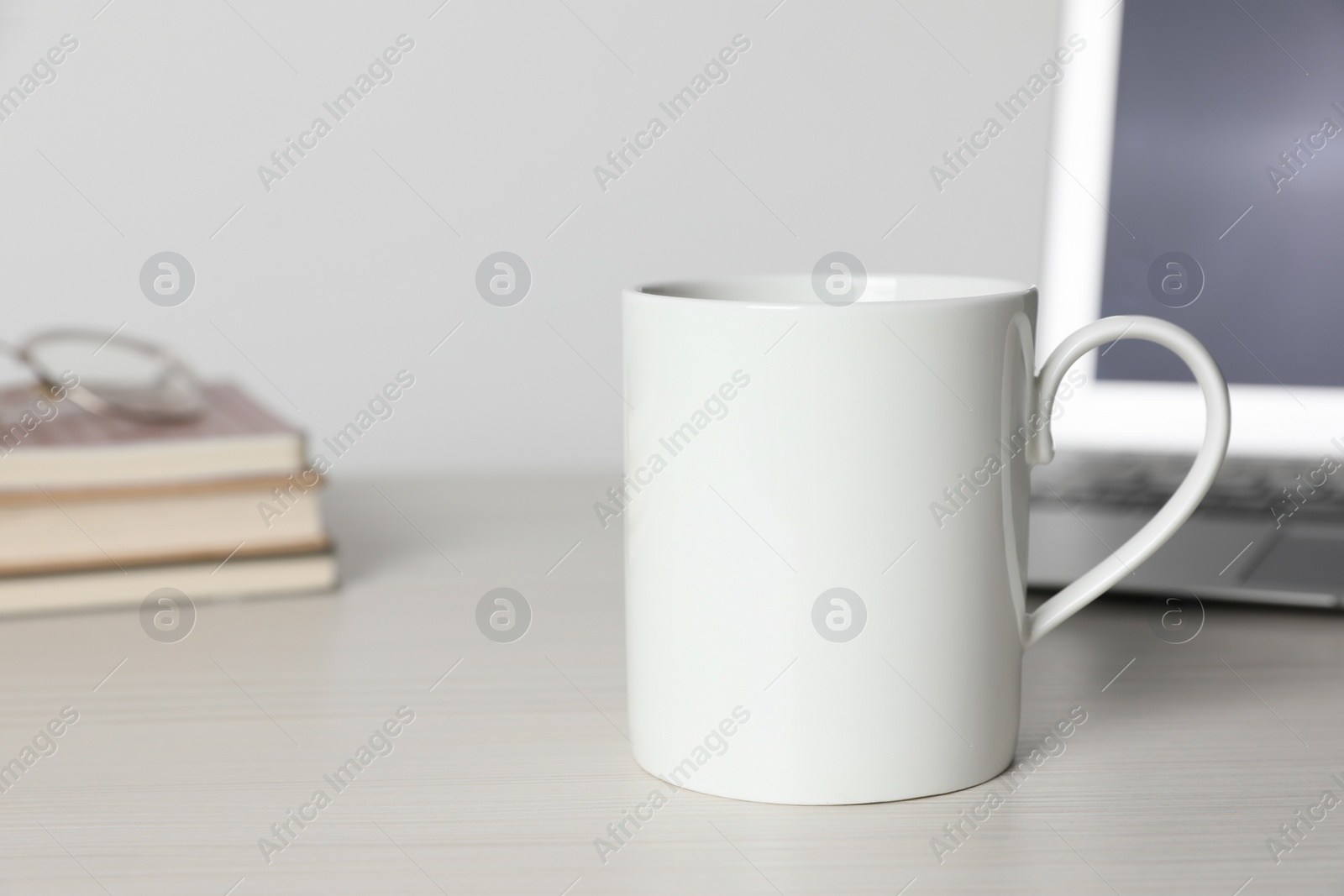 One ceramic mug with drink and laptop on white wooden table, space for text Photo of One ceramic mug with drink and laptop on white wooden table, space for text