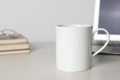 Photo of One ceramic mug with drink and laptop on white wooden table, space for text