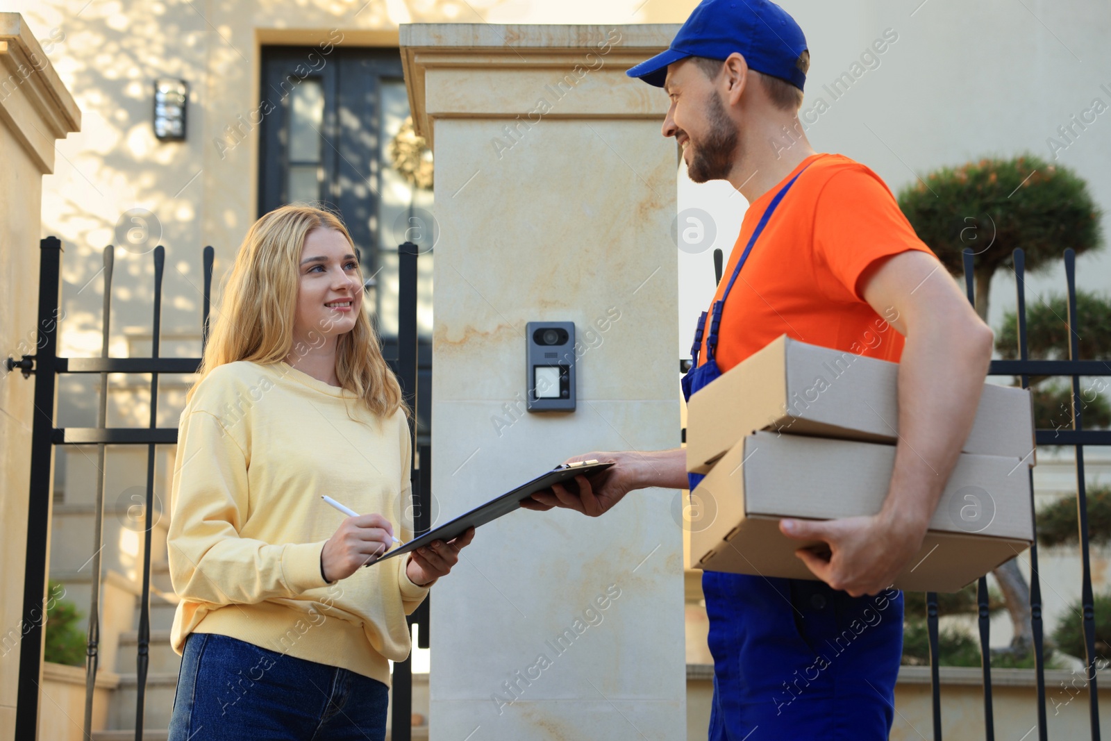 Photo of Woman signing order receipt outdoors. Courier delivery