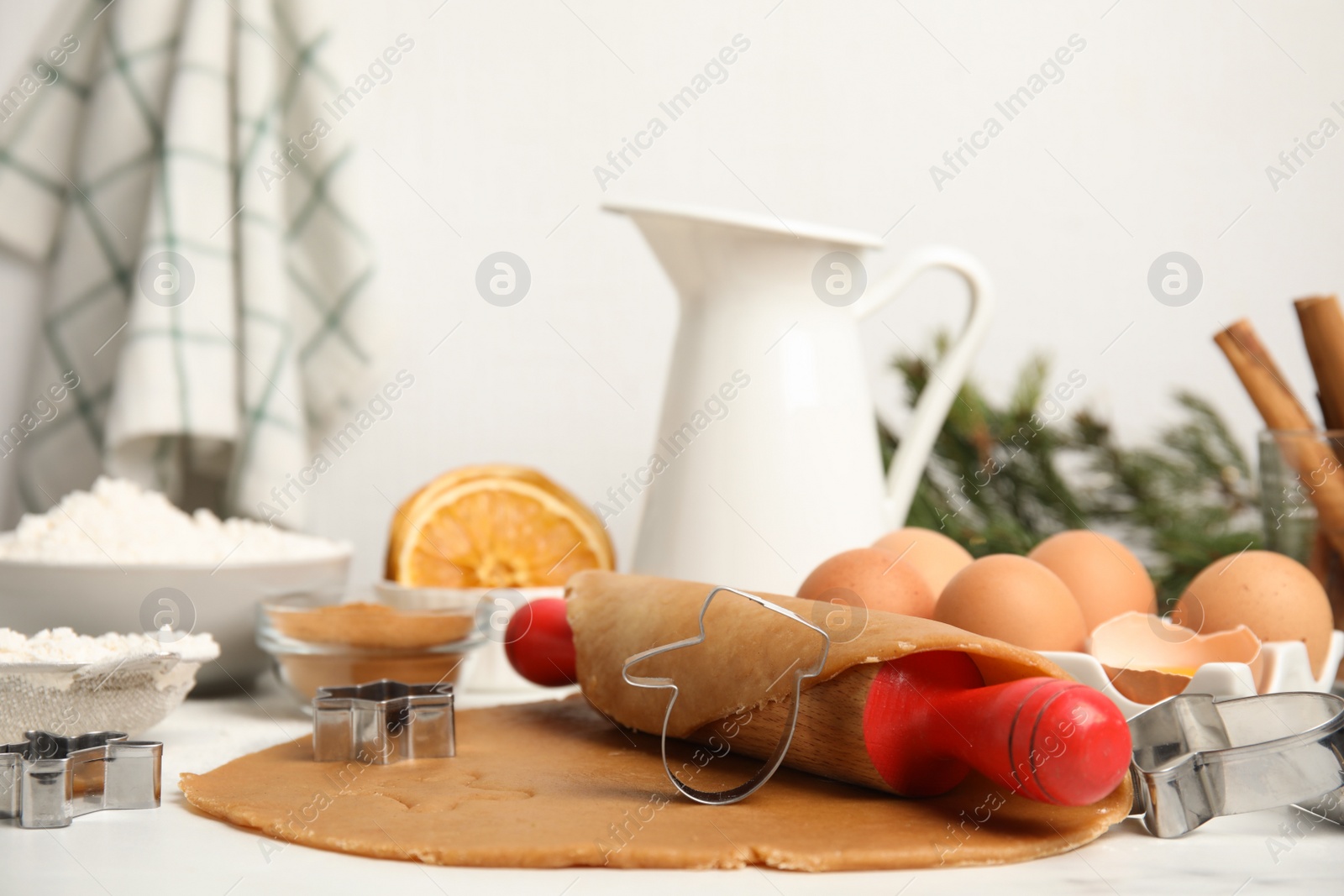 Photo of Cookie cutters, dough and rolling pin on white table. Christmas biscuits