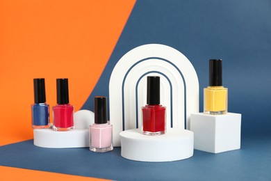 Photo of Stylish presentation of bright nail polishes in bottles on color background