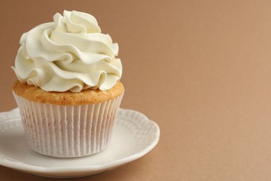 Photo of Tasty vanilla cupcake with cream on dark beige background, space for text