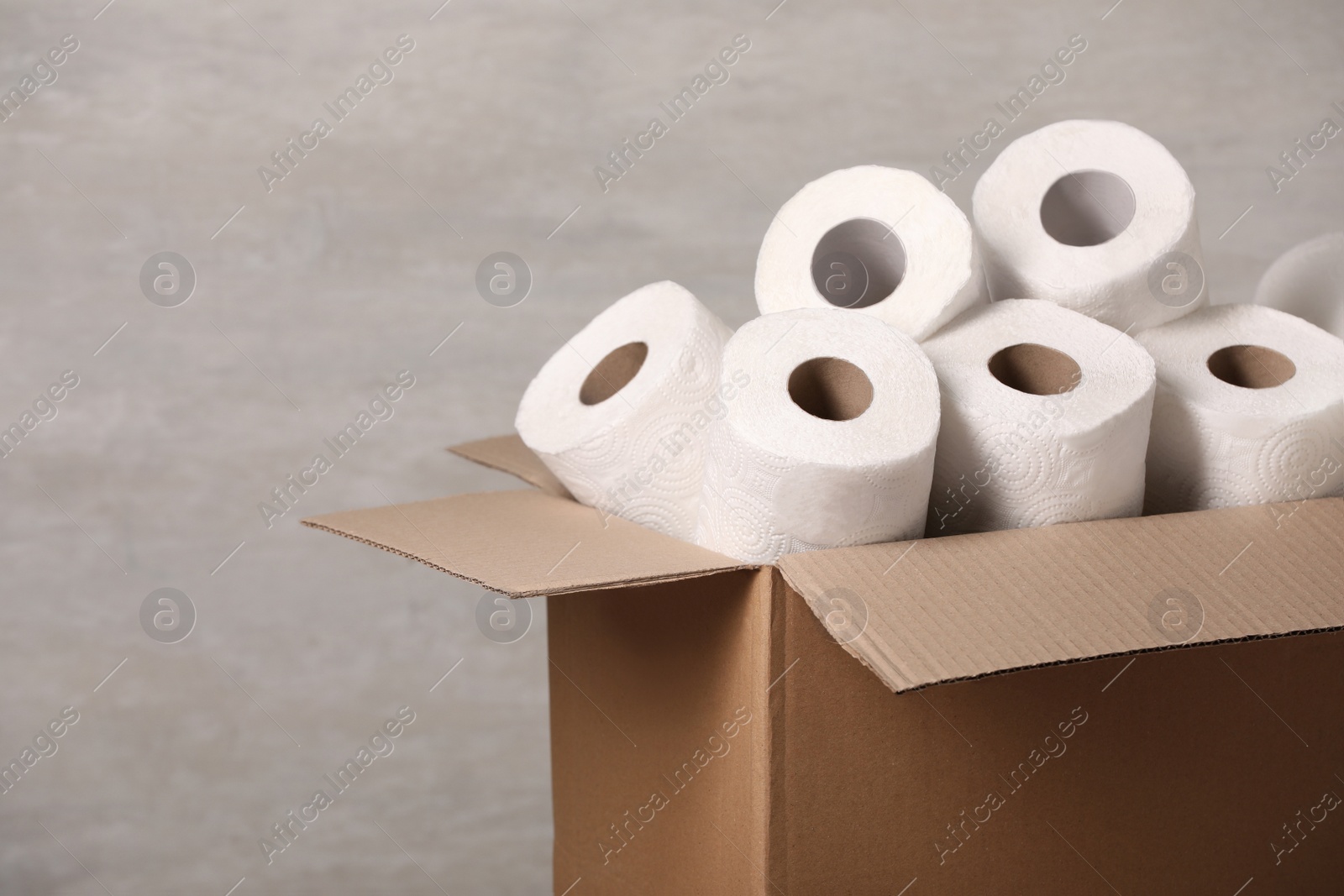 Photo of Cardboard box with paper towels on grey background. Space for text