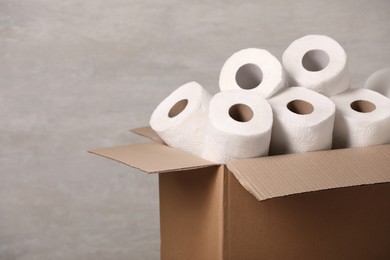 Photo of Cardboard box with paper towels on grey background. Space for text