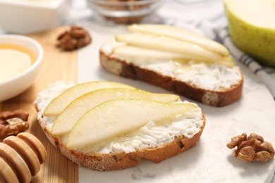 Delicious ricotta bruschettas with pear and walnut on white table, closeup