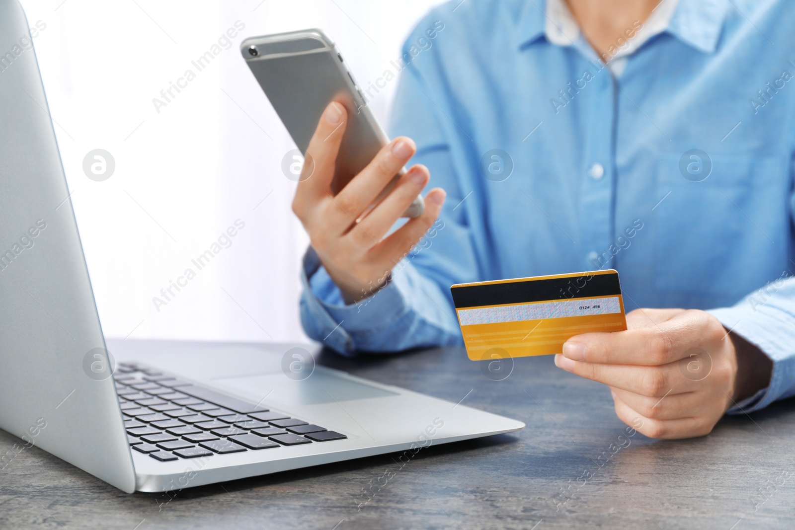 Photo of Young woman with credit card using smartphone at table
