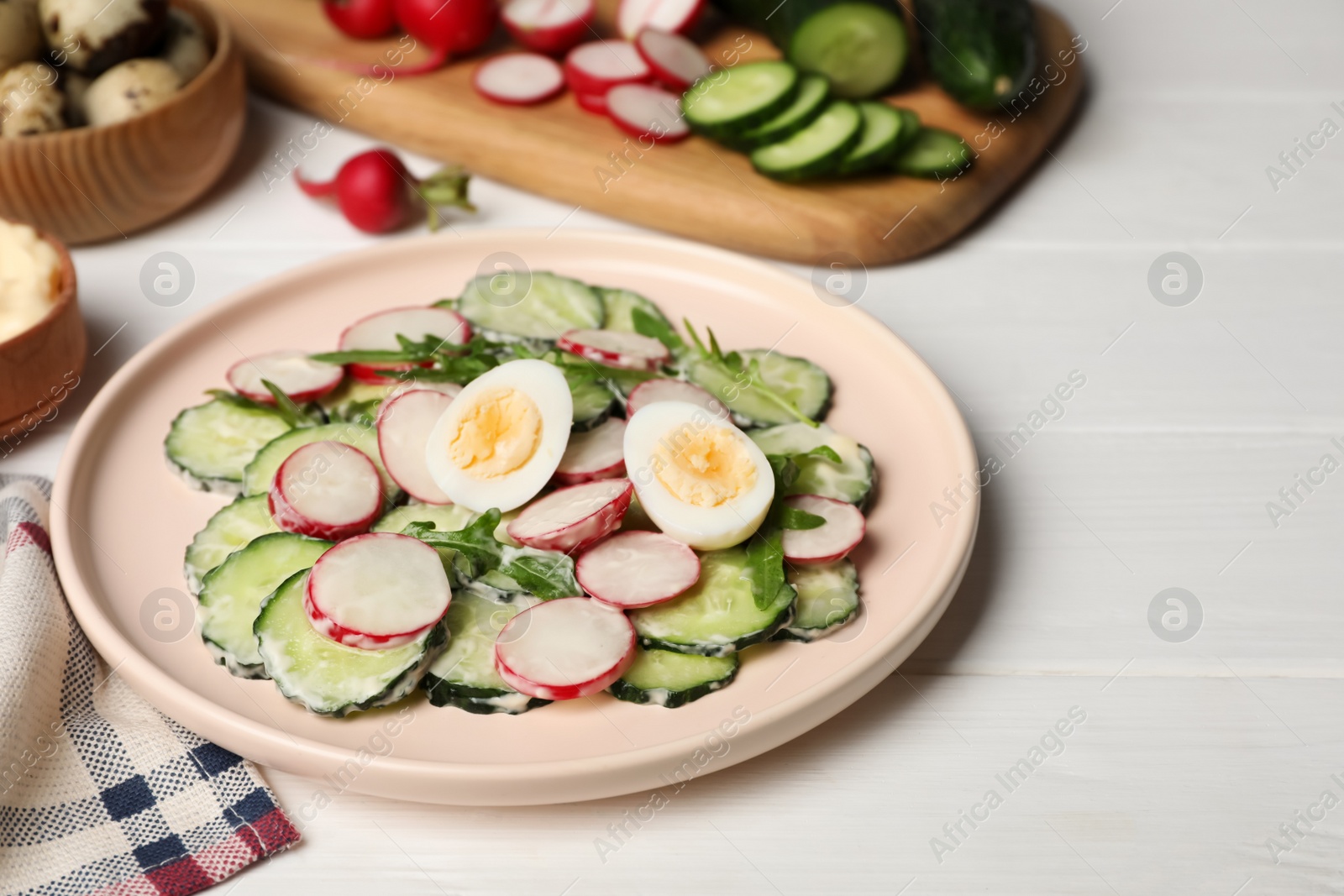 Photo of Tasty fresh salad with cucumber and ingredients on white wooden table