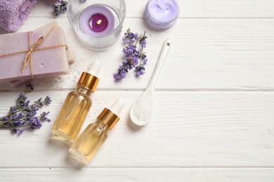 Flat lay composition with essential oil and lavender flowers on white wooden background. Space for text