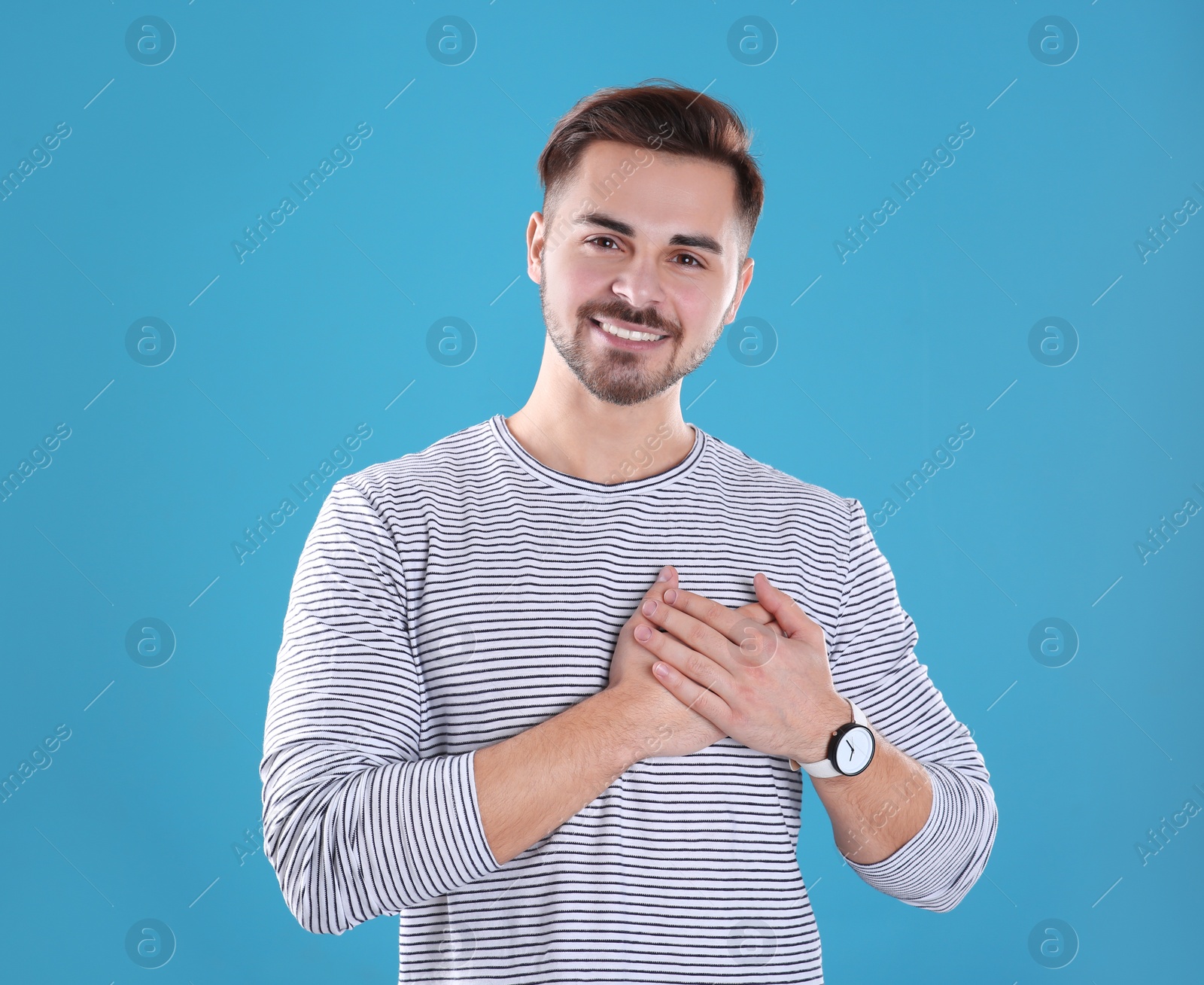 Photo of Portrait of young man holding hands near heart on color background