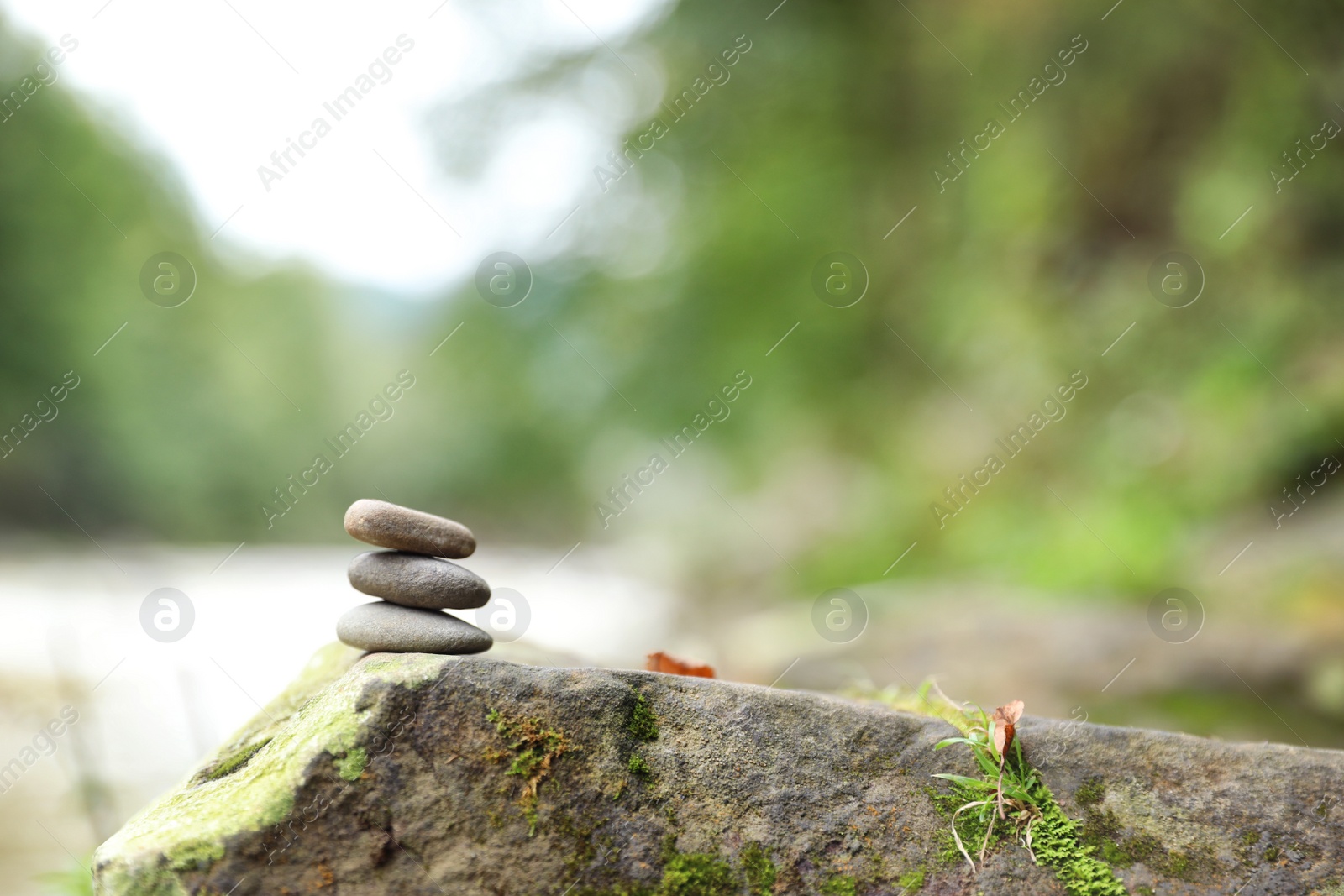 Photo of Balancing zen pebble stones outdoors against blurred background. Space for text