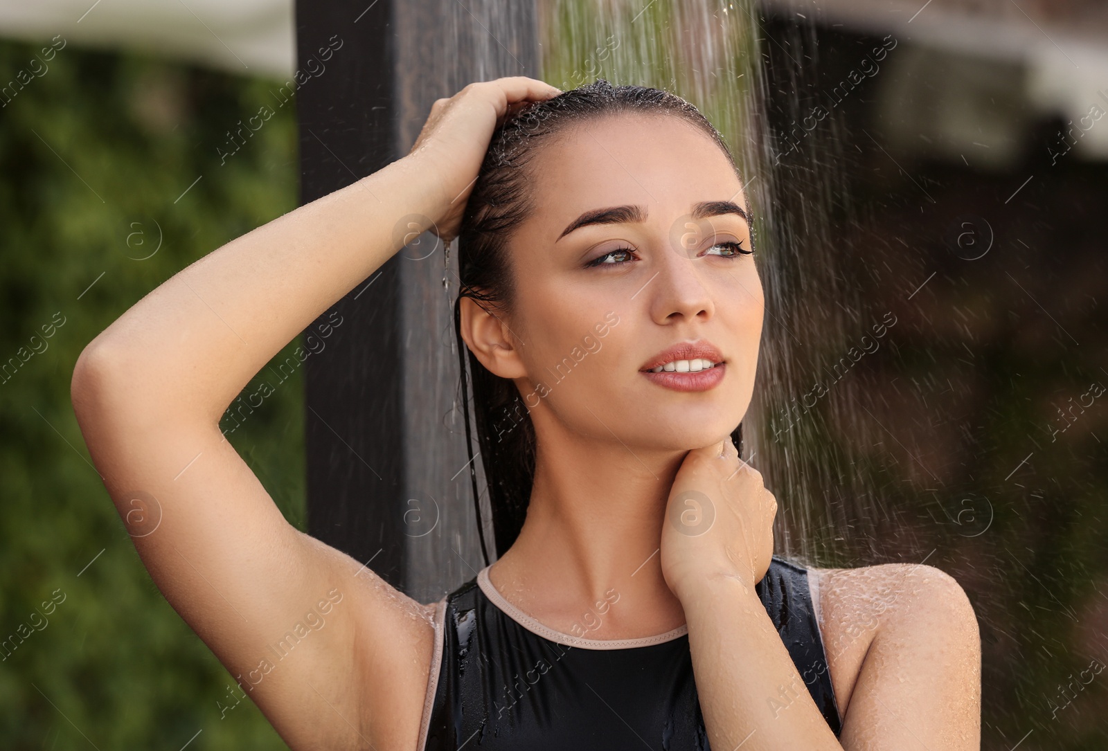 Photo of Woman washing hair in outdoor shower on summer day