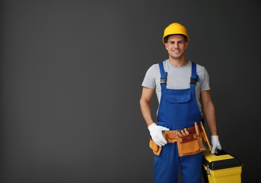 Photo of Handsome carpenter with tool box on dark background. Space for text