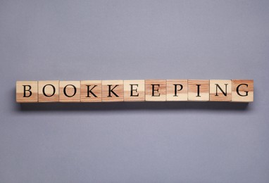Word Bookkeeping made with wooden cubes on grey background, top view