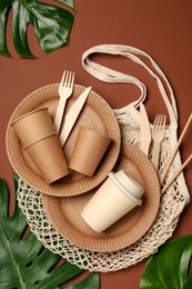 Photo of Flat lay composition with disposable tableware on brown background