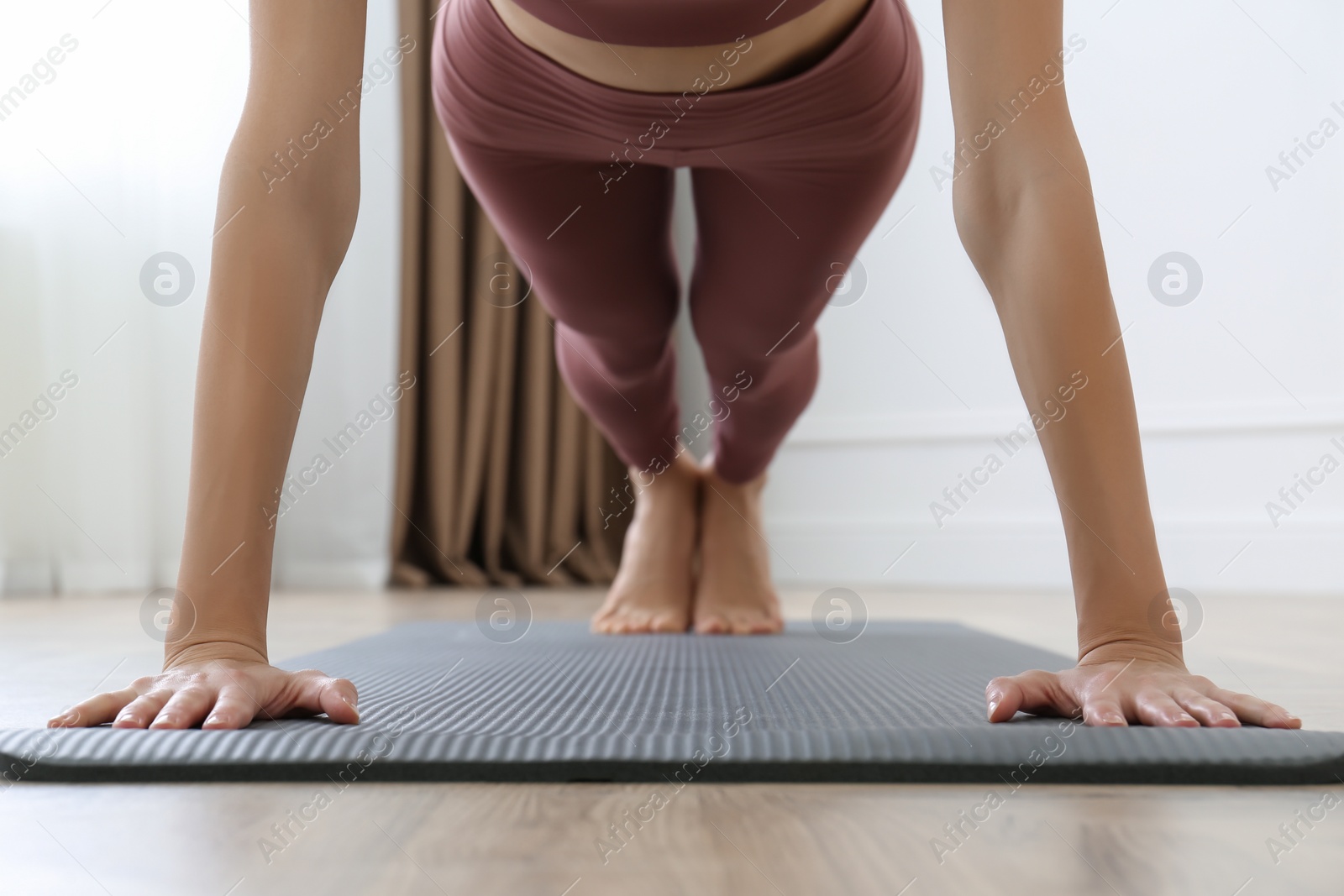 Photo of Young woman practicing plank asana in yoga studio, focus on hands. Phalakasana pose