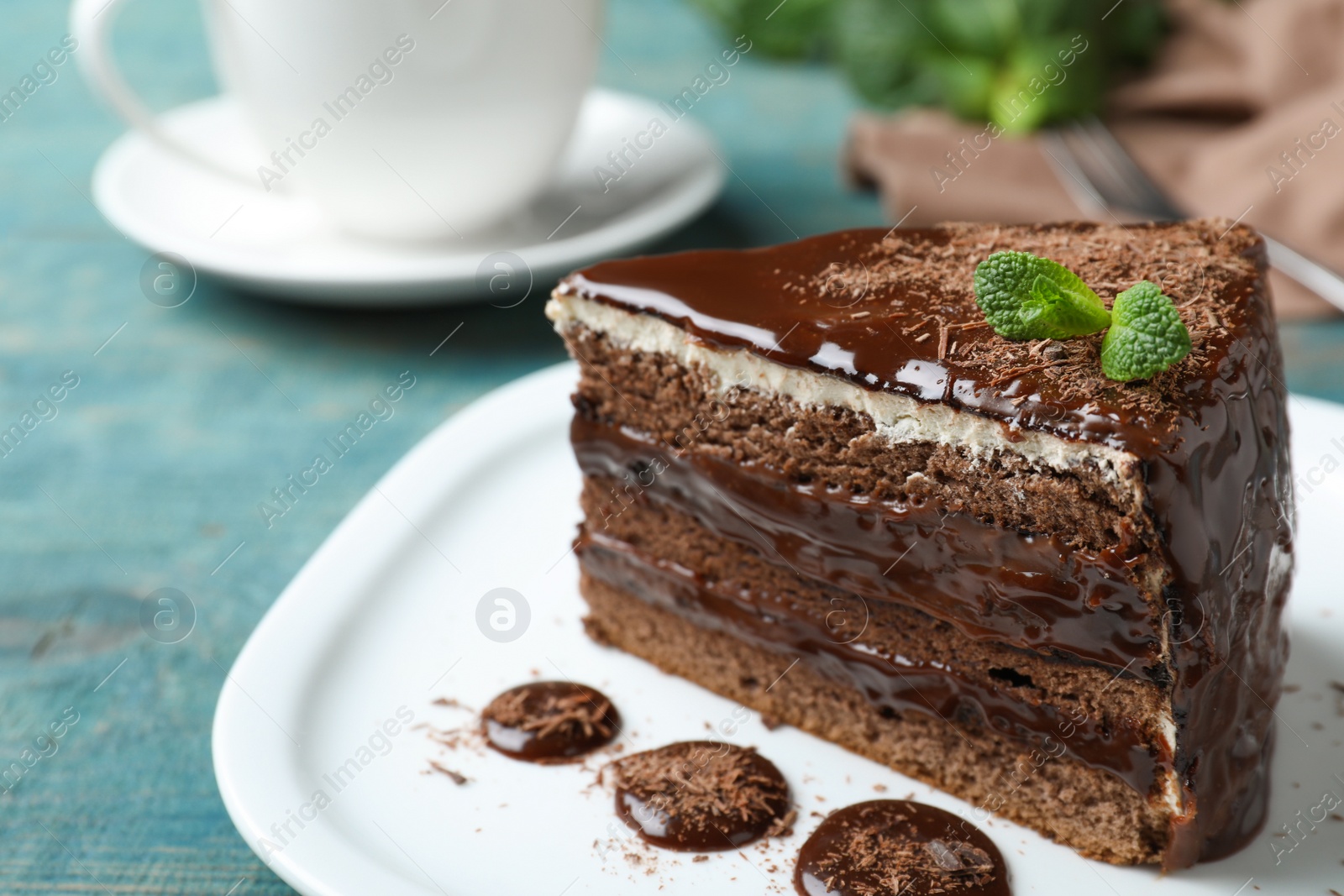 Photo of Delicious chocolate cake with mint on light blue table, closeup