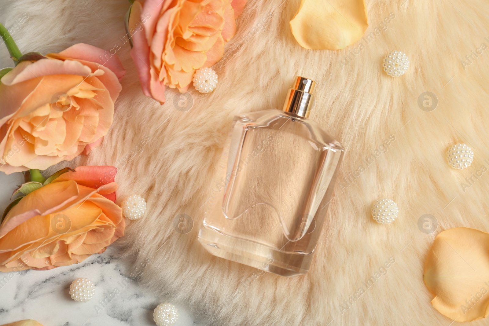 Photo of Beautiful composition with bottle of perfume on fur, flat lay
