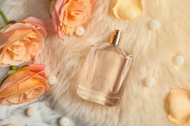 Beautiful composition with bottle of perfume on fur, flat lay