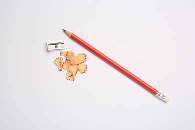 Photo of Graphite pencil, sharpener and shavings on white background, flat lay