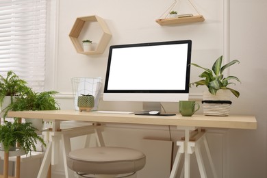 Comfortable workplace with modern computer and houseplants in room. Interior design