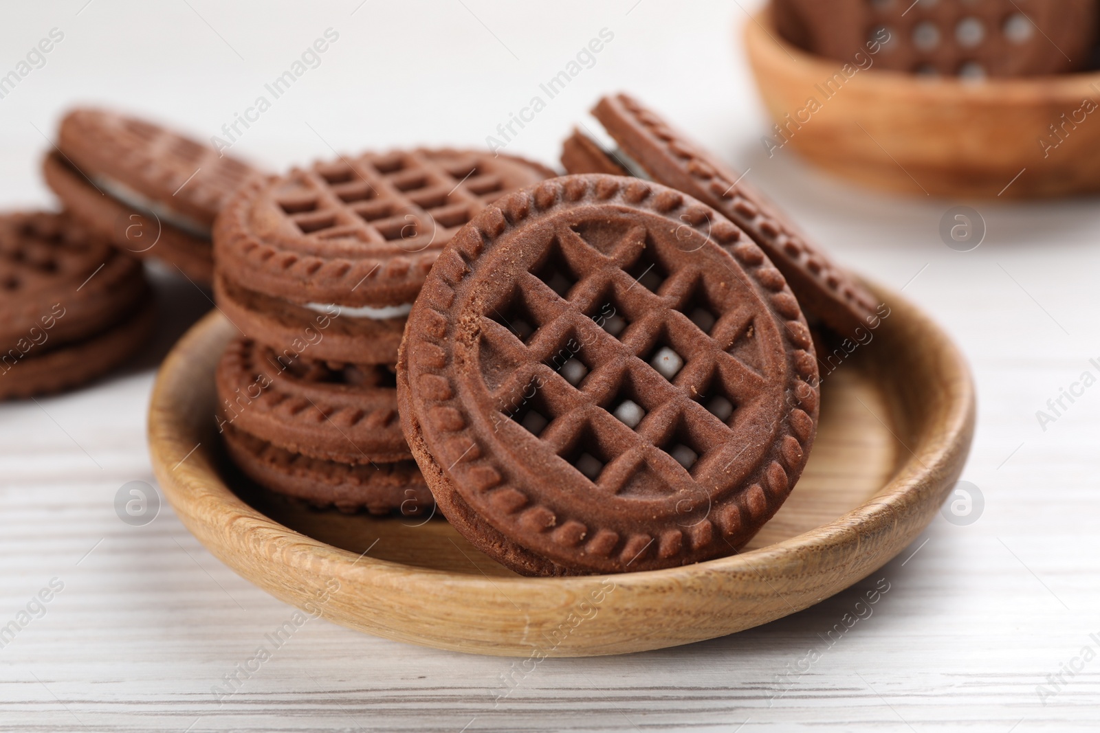 Photo of Tasty chocolate sandwich cookies with cream on white wooden table, closeup