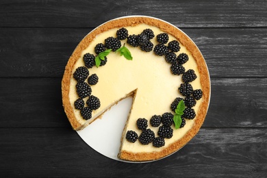 Photo of Delicious cheesecake decorated with blackberries on blue wooden table, top view