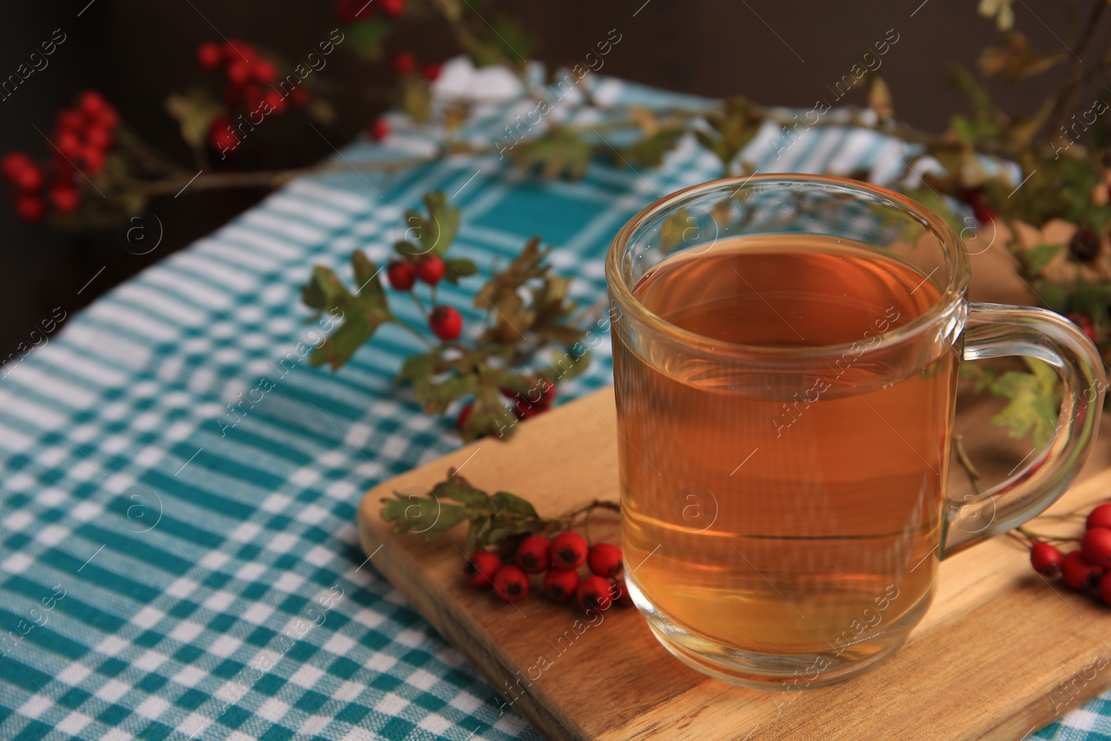 Photo of Cup with hawthorn tea and berries on table, closeup. Space for text