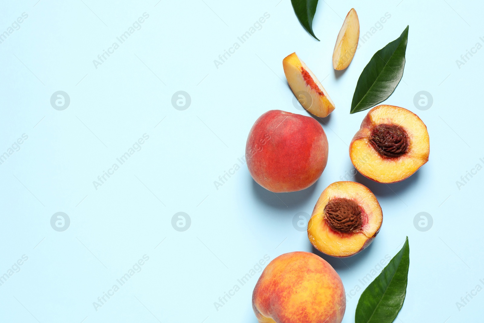 Photo of Delicious juicy peaches and leaves on light blue background, flat lay. Space for text