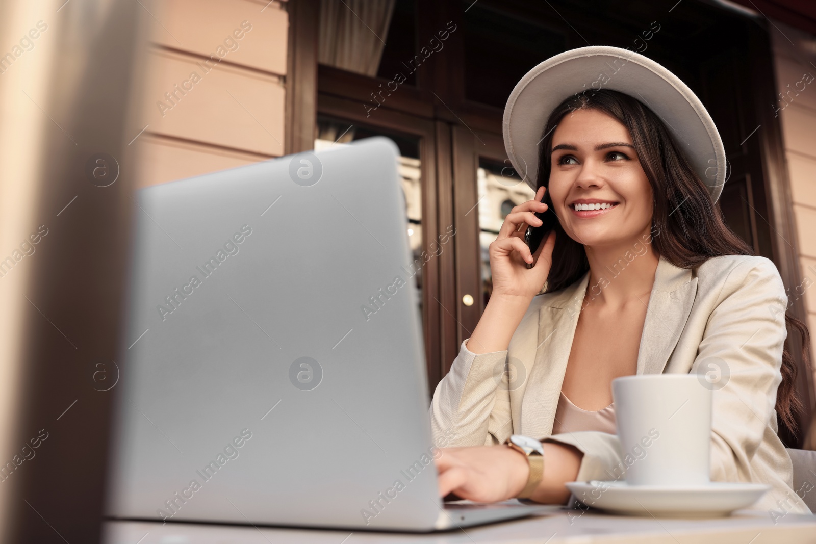 Photo of Beautiful young woman talking on phone in outdoor cafe