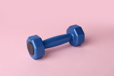 Photo of One blue dumbbell on light pink background