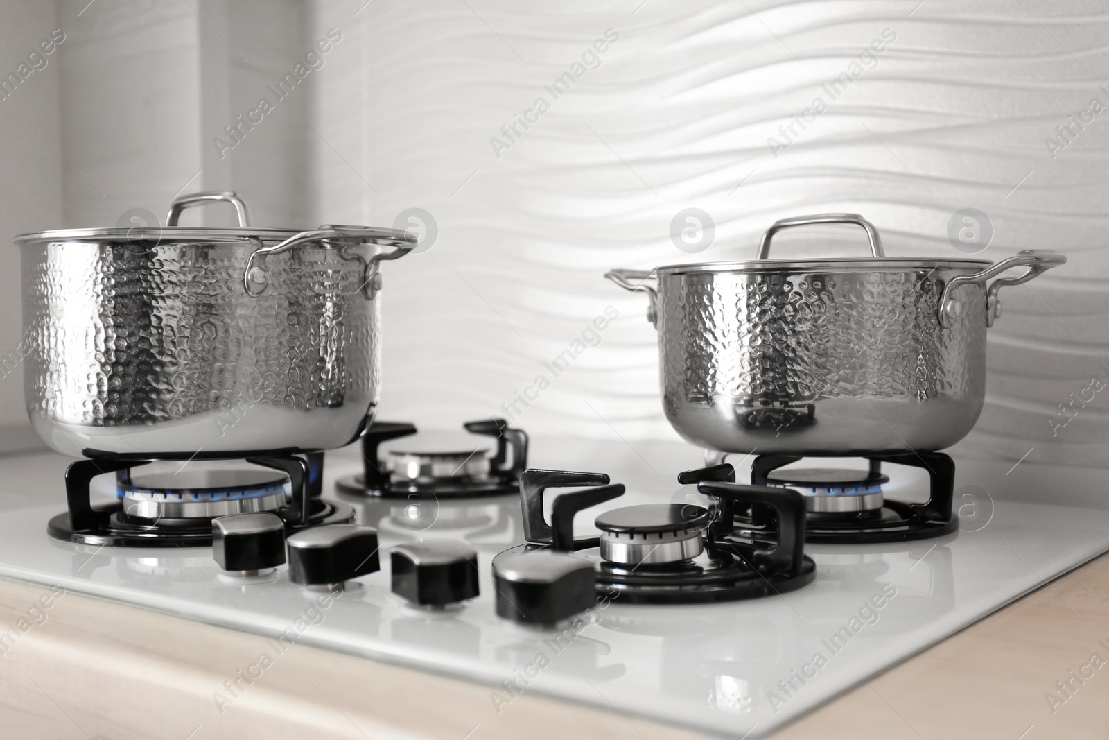 Photo of Shiny steel saucepans on modern gas stove