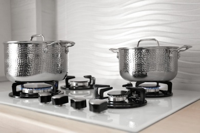 Photo of Shiny steel saucepans on modern gas stove