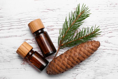 Photo of Bottlespine essential oil, conifer tree branch and cone on white wooden table, flat lay