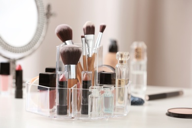 Makeup accessories and cosmetic products on table against blurred background