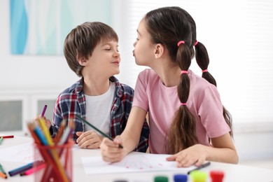 Photo of Happy brother and sister drawing at white table in room