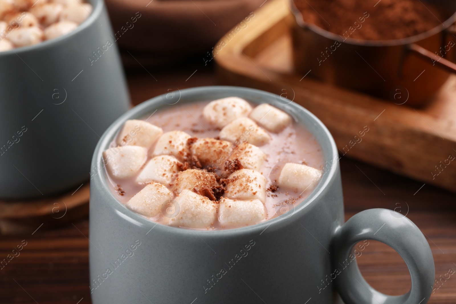 Photo of Cups of aromatic hot chocolate with marshmallows and cocoa powder on table, closeup