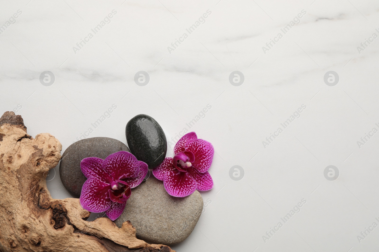 Photo of Flat lay composition with spa stones and orchid flowers on white marble table. Space for text