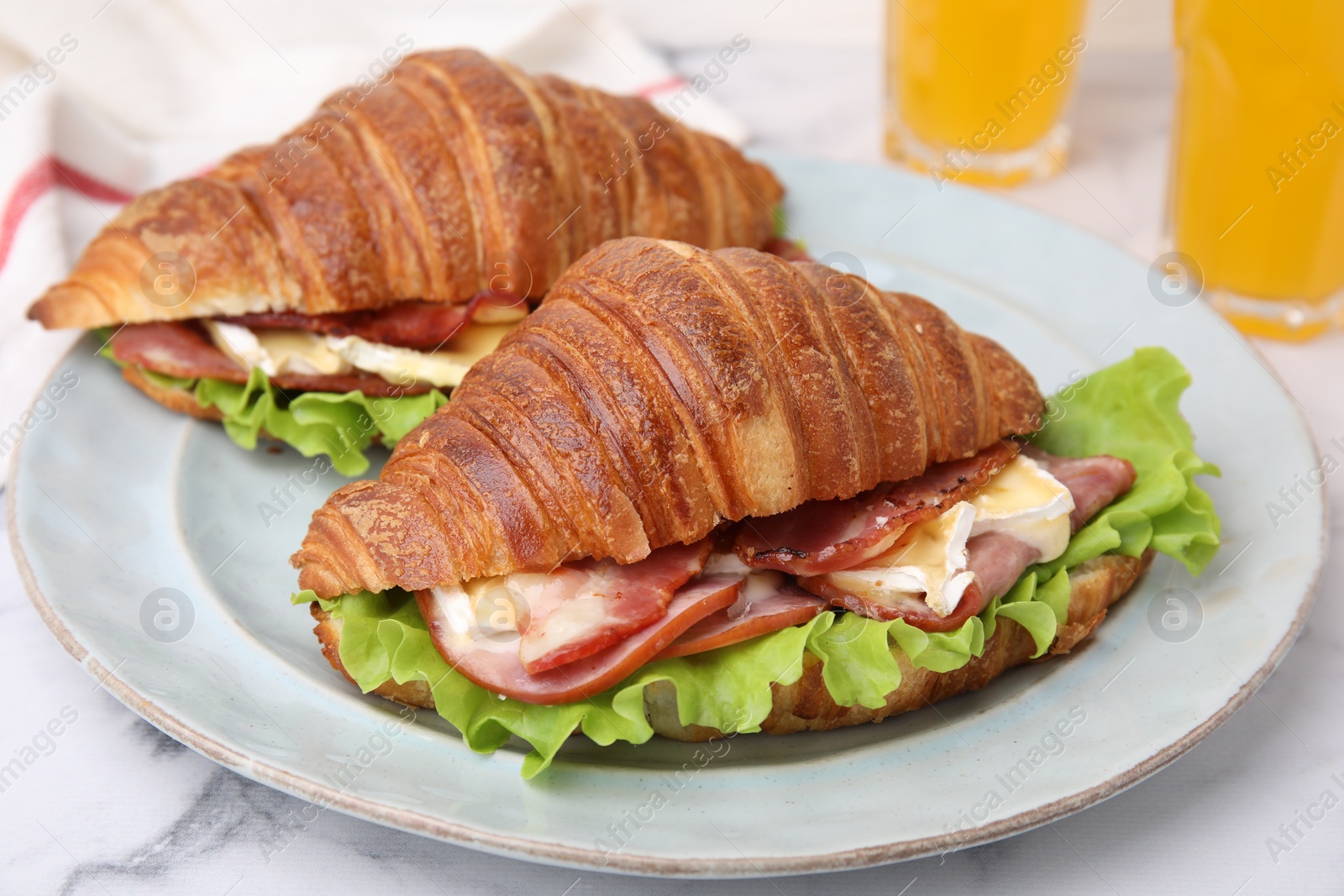 Photo of Tasty croissants with brie cheese, ham and bacon on white marble table, closeup