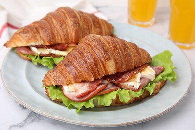 Tasty croissants with brie cheese, ham and bacon on white marble table, closeup